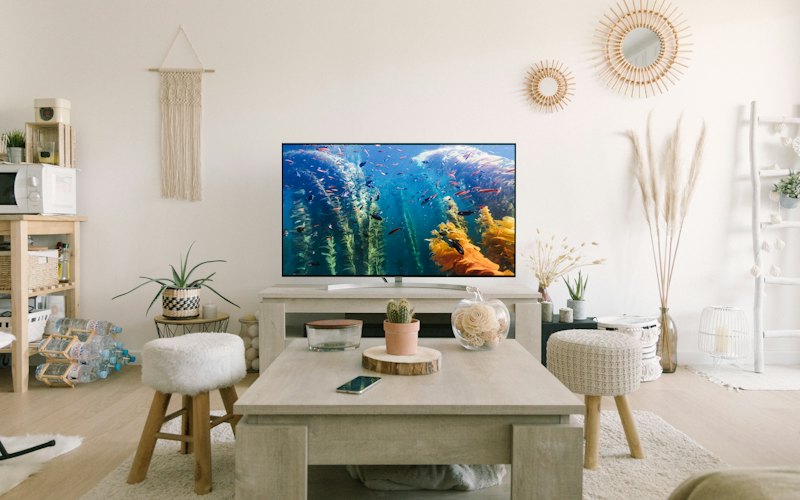 A bright living room with a big TV above a low wooden console