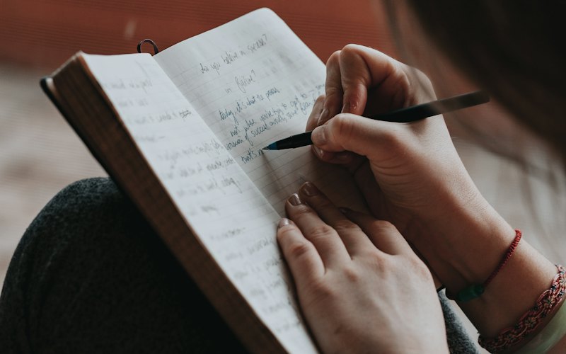 Someone writing quick notes in a small paper notebook