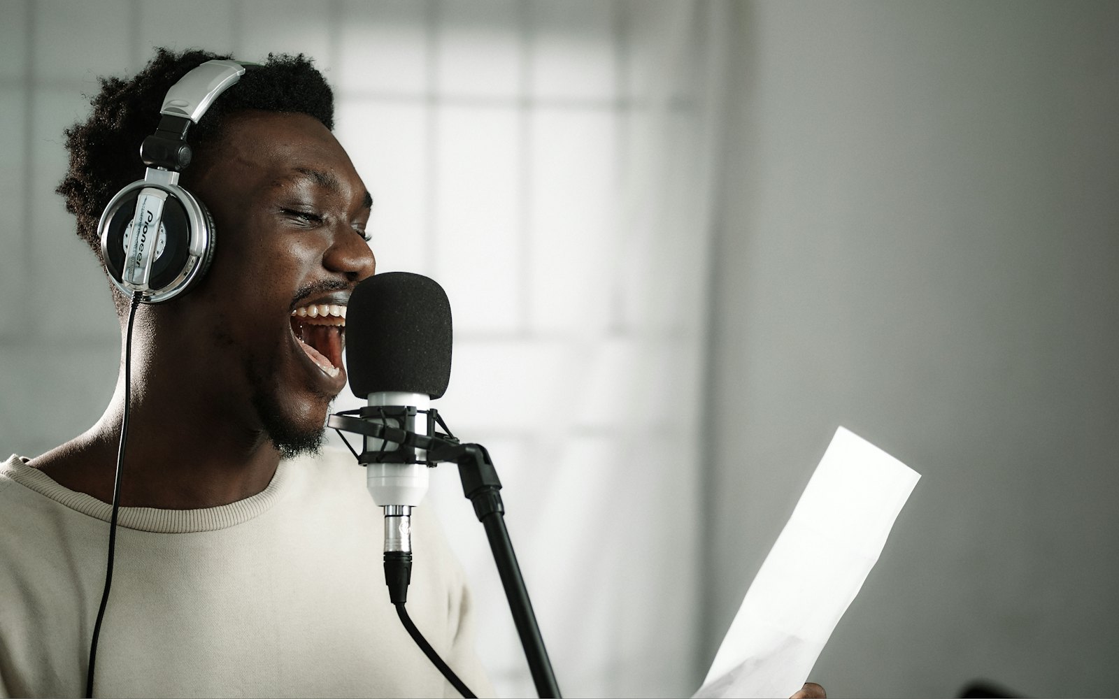 A man in headphones singing into a studio microphone