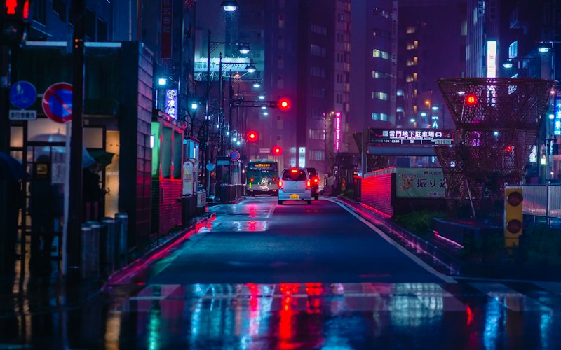 A rain-soaked Tokyo street at night, neon signs reflected on the asphalt